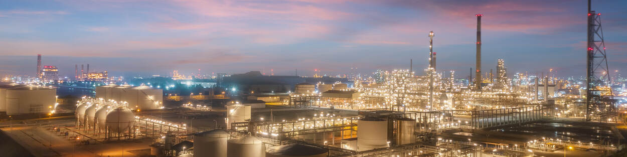 A refinery at dusk, with lights on.