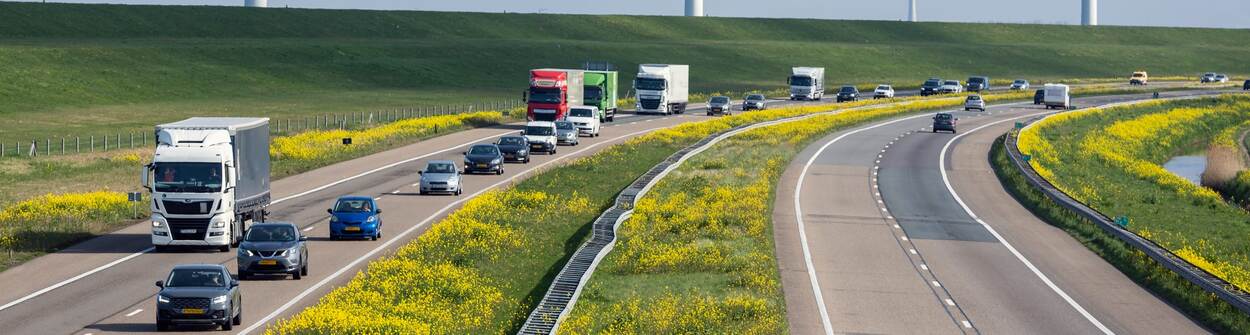 Two parallel roads surrounded by grass, with some traffic on them.